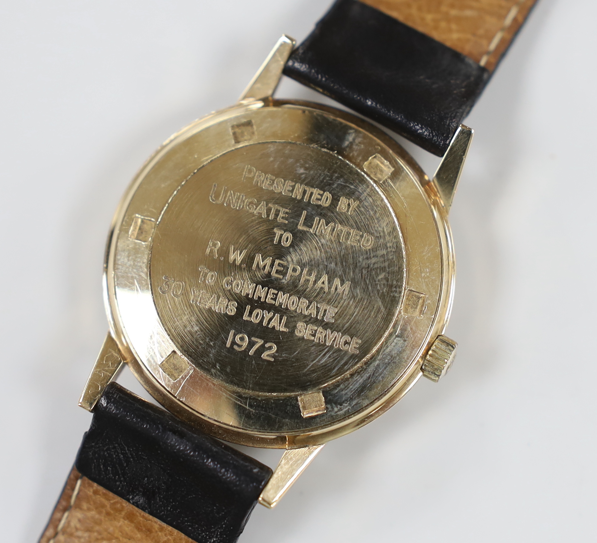 A gentleman's early 1970's 9ct gold manual wind wrist watch, retailed by Garrards, with case back inscription, on a leather strap.